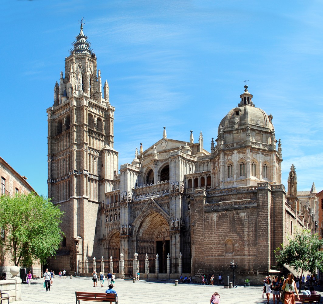 a group of people walking in front of a church with Toledo Cathedral in the background