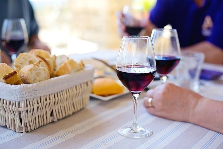 Table with wine glasses, bread basket, and people dining.