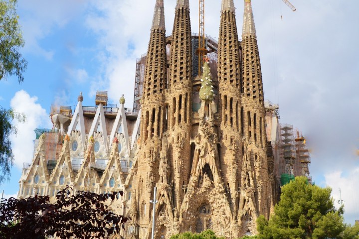 a large clock tower towering over the city of london with Sagrada Família in the background