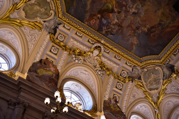 Ornate ceiling with arches, chandeliers, and fresco paintings.