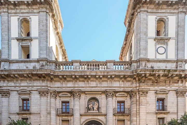 Facade of a historic stone building with two towers and arched entrance.