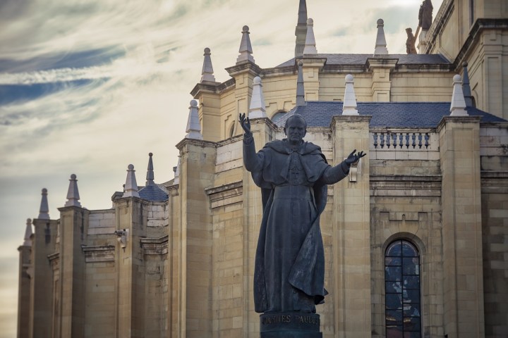 Statue of a standing figure outside a historic building with spires.